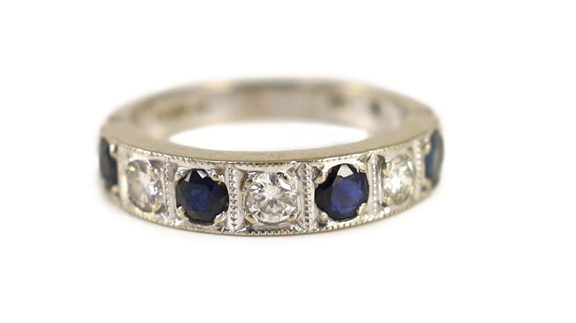 A 1970's 18ct white gold, four stone sapphire and three stone diamond millegrain set half eternity ring